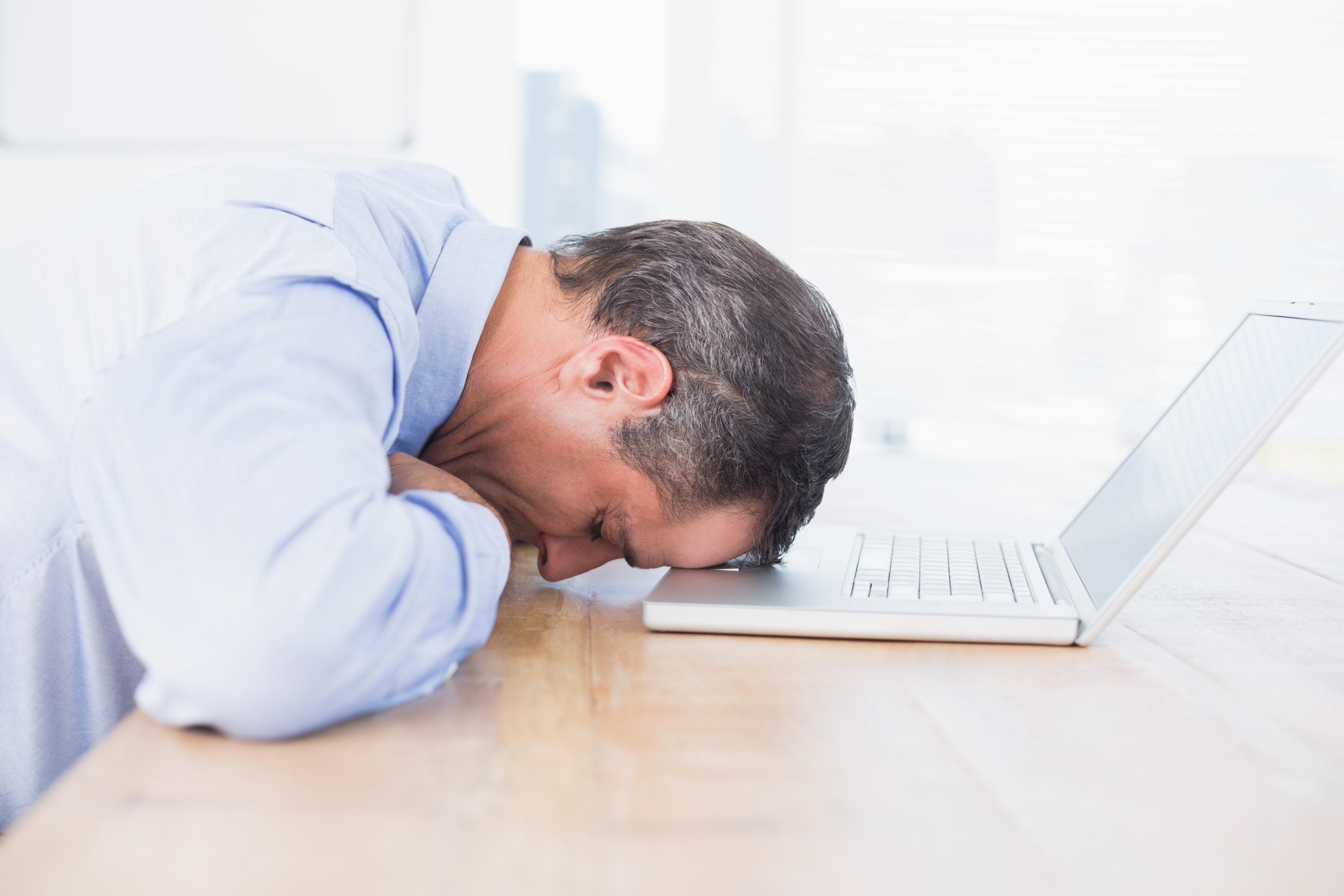 Man with his head on laptop computer 
